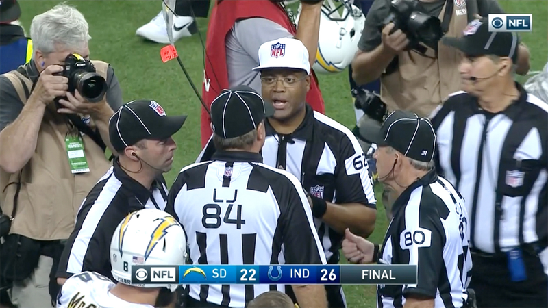 Referee Ron Torbert discusses an end-of-game call with his officiating crew. (Screenshot: CBS)
